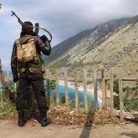 A Syrian rebel fighter stands on a ridge overlooking the Mediterranean Sea, reportedly in the village of Kasab, in the northwestern province of Latakia, on April 4. | AFP-JIJI