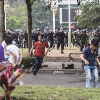 People run as Chinese riot police officers try to disperse protesters against a chemical plant project in Maoming, Guangdong province, on Monday. | REUTERS