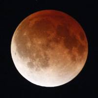 A shadow falls on the moon as it undergoes a total lunar eclipse as seen Tuesday from Mexico City as the orb moves into Earth\'s shadow, taking on an orange, red or brown glow. | REUTERS