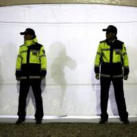 Police officers stand guard outside a tent acting as a temporary morgue for victims of the sunken South Korean ferry Sewol at the port of Jindo on Saturday. Some relatives of the more than 200 teenagers missing in the sunken vessel offered DNA swabs on Saturday to help identify the dead. | REUTERS