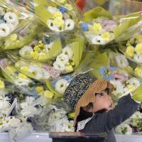 A girl presents flowers at a ceremony held Friday to mark the ninth anniversary of the JR West Fukuchiyama Line train derailment in Amagasaki, Hyogo Prefecture, in 2005 that claimed 107 lives. | KYODO
