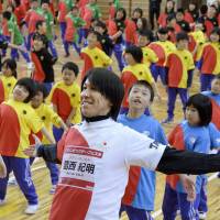 Ski jumper and Sochi Olympics silver medalist Noriaki Kasai exercises with students Monday at Funakoshi Elementary School in the town of Yamada, Iwate Prefecture. Kasai and other top athletes visited the recently reopened school to show their support for the town\'s reconstruction efforts following the March 2011 earthquake and tsunami. | KYODO