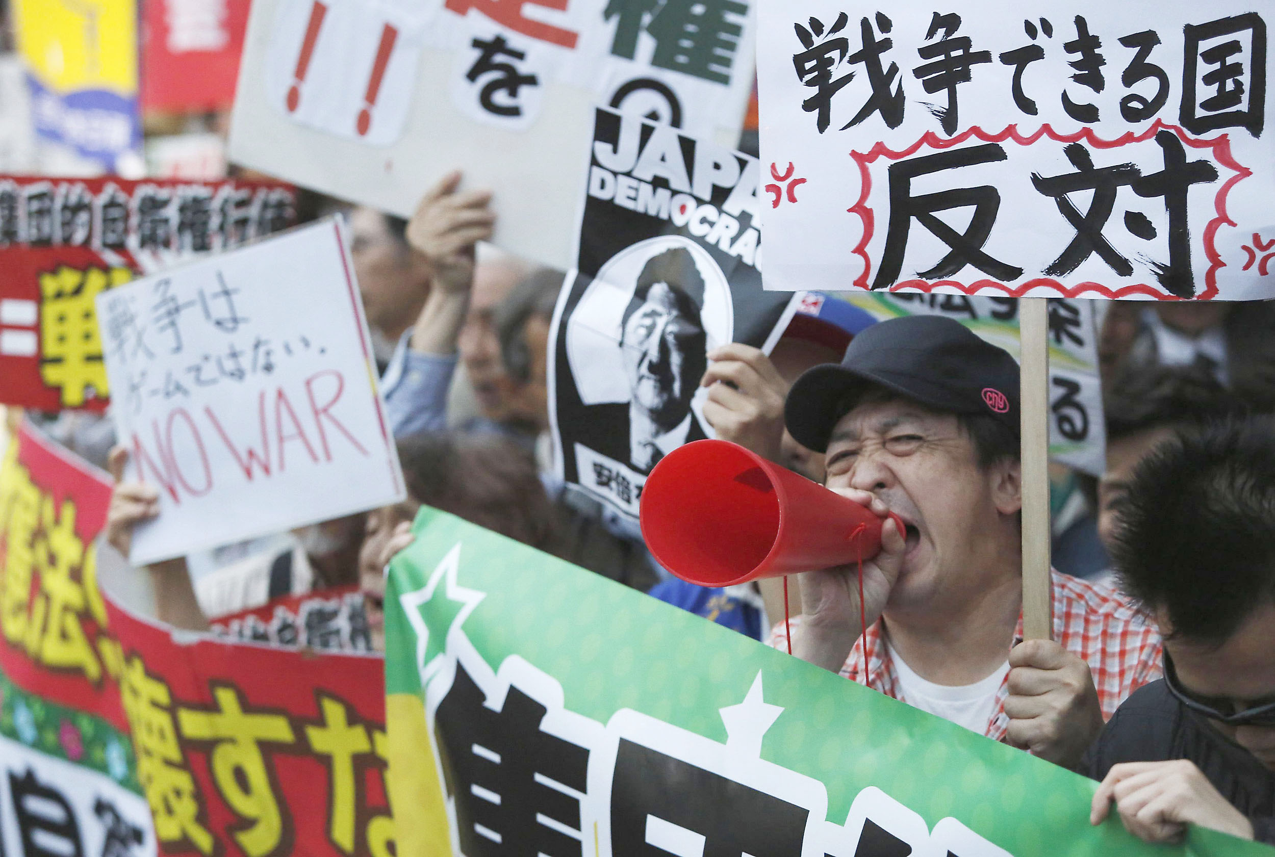 A protester voices his opposition to reinterpreting Article 9 of the Constitution in Tokyo on Thursday. | REUTERS
