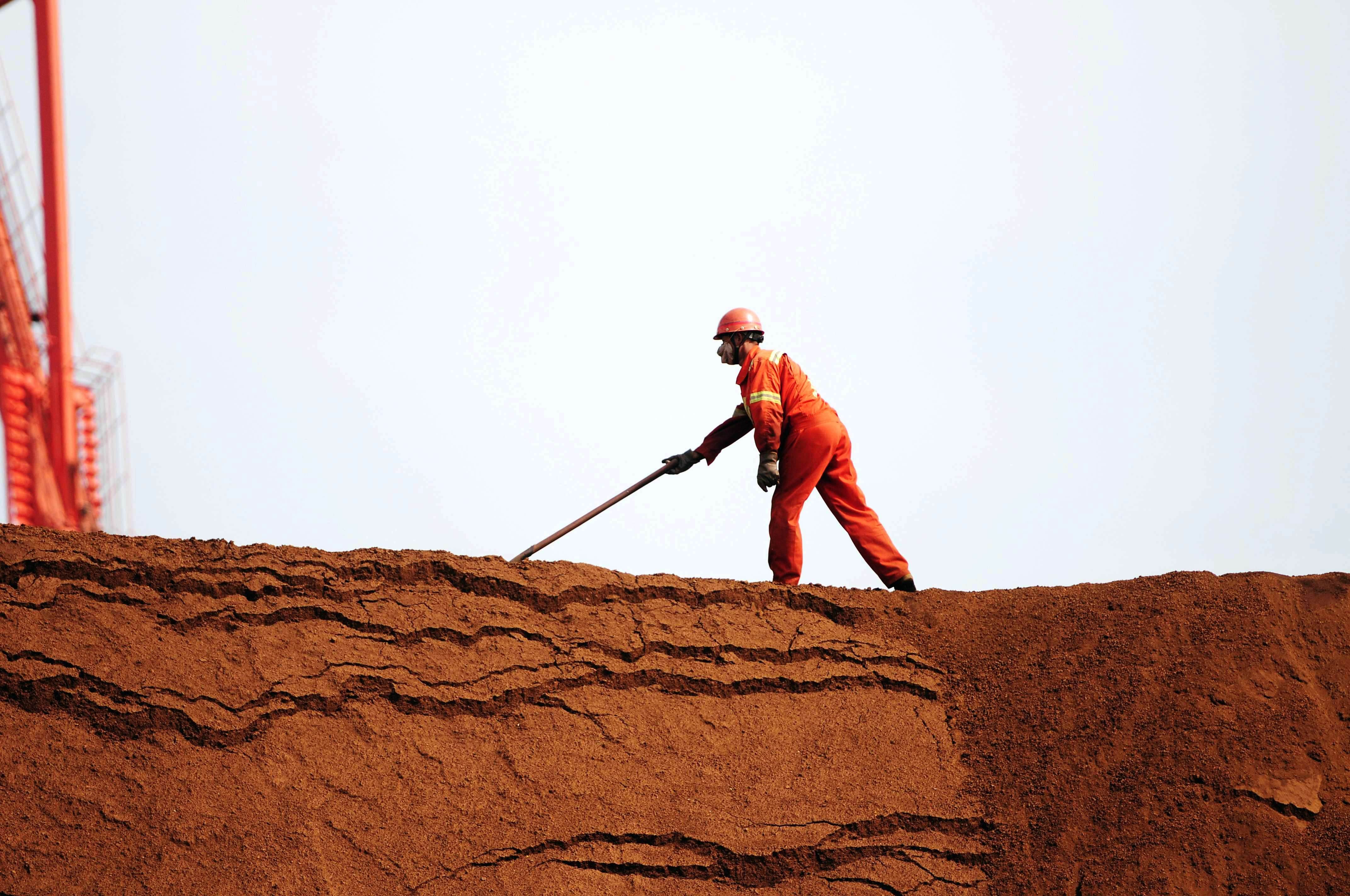A worker unloads iron ore in Qingdao, China, on Thursday. A two-day meeting of APEC trade ministers hosted by the city ended Sunday with an agreement to draft a road map for creating a new free trade area in the region, possibly by the end of the year. | AFP-JIJI