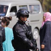 A Chinese SWAT unit guards the Urumqi railway station where three people died in a bomb and knife attack Wednesday. | REUTERS