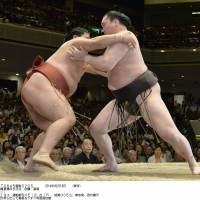 Man down: Hakuho (right) gets to grips with Yoshikaze at the Summer Grand Sumo Tournament on Sunday. | KYODO