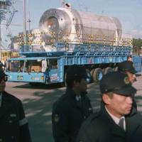 Riot police escort a canister containing 20 tons of nuclear waste from France in May 1997 as it is transported to a storage depot from a port in the northern village of Rokkasho, Aomori Prefecture. | AP