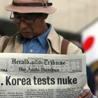 A pedestrian in Tokyo reads a special edition announcing North Korea’s nuclear test in October 2006. Any nuclear test by Japan in future would likely cause a domestic and international uproar of a similar scale. | BLOOMBERG