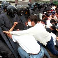 Students in Gwangju push riot police during an anniversary rally on May 19, 1996. | AP