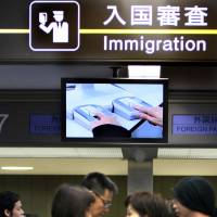 First stop: People head toward the immigration area at Narita International Airport in Chiba Prefecture. Upon arrival, foreigners have their picture taken by a machine that also scans their fingerprints. | BLOOMBERG