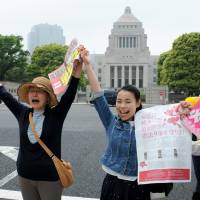 Outside the Diet building Tuesday, activists form a human chain in solidarity against Prime Minister Shinzo Abe\'s shortcut plan to reinterpret the Constitution to allow Japan to legally exercise the right to collective self-defense. | SATOKO KAWASAKI