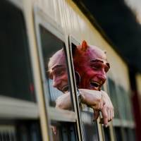 A man in devil makeup looks out of a railway car as he travels through the Harz mountains to celebrate the Walpurgisnacht pagan festival on Wednesday. | REUTERS