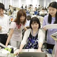Employees work in casual attire at the Environment Ministry in Tokyo on Thursday. | KYODO