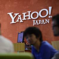 Yahoo Japan Corp. employees speak to a customer in front of the company\'s headquarters in Tokyo last year. | BLOOMBERG