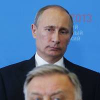 President Vladimir Putin stands behind Russian Railways chief Vladimir Yakunin at the St. Petersburg International Economic Forum in June 2013. | REUTERS