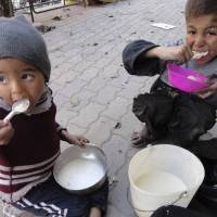 Children eat at the besieged Yarmouk refugee camp, south of Damascus, in April. | REUTERS