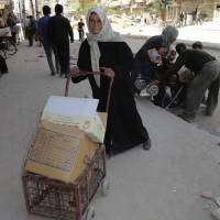 A Palestinian receives food aid distributed by the United Nations at the Yarmouk refugee camp, south of Damascus, on April 25. | REUTERS