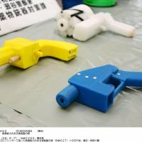 Kanagawa police on Thursday display two guns (yellow and blue) created with a 3-D printer that can fire real bullets.  | KYODO