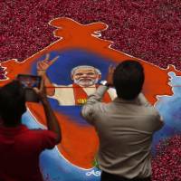 Indians take photographs of a portrait of Bharatiya Janata Party leader Narendra Modi made with colored powder and surrounded by rose petals at the party offices in Gandhinagar, in the western Indian state of Gujarat, on Friday. | AP