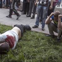 A man kneels next to the body of a pro-Russia activist killed in Krasnoarmeisk, Ukraine, on Sunday. Although the voting in the Donetsk and Luhansk regions appeared mostly peaceful, Ukrainian national guardsmen opened fire on a crowd outside a town hall in Krasnoarmeisk, and an official with the region\'s insurgents said there was at least one fatality. | AP