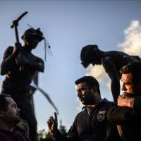 People gather in front of a statue representing a miner holding a shovel in the western Turkish town of Soma on Saturday. A search for victims of last Tuesday\'s mine explosion ended Saturday, and the final death toll was put at 301. | AFP-JIJI