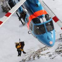 A Nagano Prefectural Police rescue squad on a helicopter lift an unidentified climber from Mount Hotaka on Tuesday. | KYODO