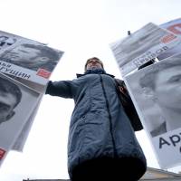 A woman holds portraits of Russian opposition protesters in central Moscow on Tuesday, as activists mark the second anniversary of a chaotic anti-Kremlin protest in Bolotnaya Square on May 6, 2012, that descended into violence and preceded Putin\'s return to the presidency a day later. | AFP-JIJI