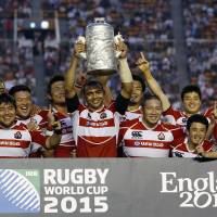 See you in England: Japan captain Michael Leitch lifts the trophy as the Brave Blossoms celebrate their win over Hong Kong on Sunday. Japan claimed the Asian Five Nations title and a spot in the 2015 Rugby World Cup with the win. | AP