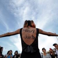 A protester with messages written on her back and arms joins others demonstrating against military rule at the Victory Monument in Bangkok on Saturday. | REUTERS