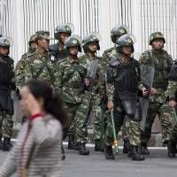 Paramilitary police with shields and batons patrol near the People\'s Square in Urumqi, the capital of Xinjiang, on Friday. | AP