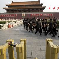 Security guards march Saturday past the site where a man crashed an SUV and set the vehicle on fire after mowing down a crowd of tourists in front of Tiananmen Gate, Beijing, on Oct. 28. | AP