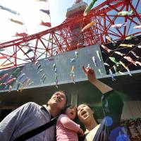 A family views \"koinobori\" (carp streamers) at Tokyo Tower on Sunday ahead of Children\'s Day on May 5. The event has drawn about 20,000 visitors a day. | YOSHIAKI MIURA