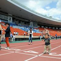 A toddler stands on the track at National Stadium in Shinjuku Ward, Tokyo, on Friday. More than 10,000 people have taken a final look at the venue for the 1964 Tokyo Olympics, which was opened for public viewing the same day ahead of its scheduled demolition in July. The 56-year-old stadium will make way for a new stadium that will host the main ceremonies for the 2020 Tokyo Olympics and Paralympics. More public viewings are scheduled for May 4, 7 and 22. | SATOKO KAWASAKI