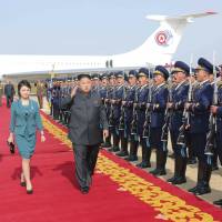 North Korean leader Kim Jong Un salutes as he and his wife, Ri Sol Ju, walk past an honor guard upon arriving for the 2014 Combat Flight Contest among commanding officers of the Korean People\'s Air Force in this undated photo. Behind them is what appears to be Kim\'s own version of the U.S. president\'s private plane, Air Force One. | REUTERS