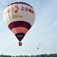 Hot-air balloons float over the town of Kamishihoro in Hokkaido last August. The town, known for the sport, is rewarding taxpayers with free flights. | KAMISHIHORO MUNICIPAL GOVERNMENT/KYODO