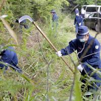 Police investigators on Sunday search for Mayuko Arakawa\'s belongings at the site where a body was found on a mountainside in Hitoyoshi, Kumamoto Prefecture. | KYODO