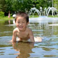 The heat wave brought enjoyment to some people in often chilly northern Japan, including these children, who cooled off in a park in Asahikawa, Hokkaido, on Tuesday. | KYODO