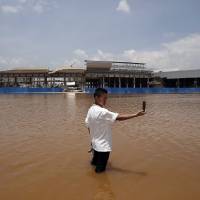 In the wash: A resident stands in a flooded area of Wujiaba airport in Yunnan Province, China earlier this month. As a result of global warming, the wet areas of the world are getting wetter and the dry areas drier, with water conflicts already a reality. | REUTERS