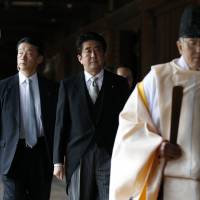 Prime Minister Shinzo Abe is led by a Shinto priest as he visits Yasukuni Shrine in Tokyo on Dec. 26. | REUTERS