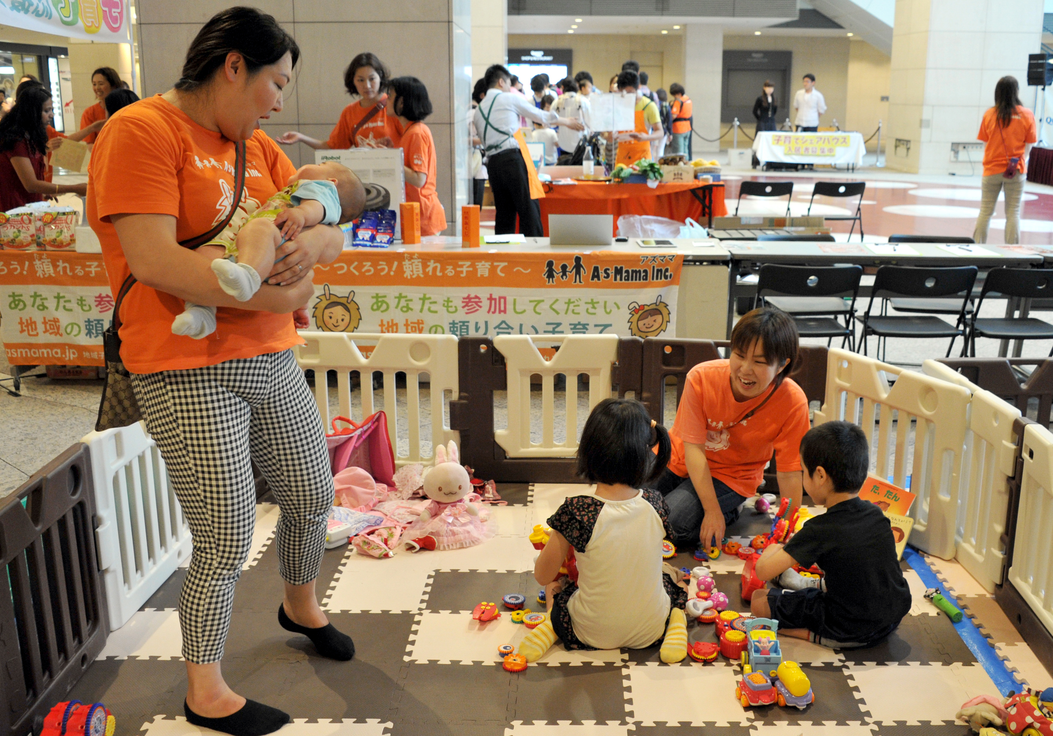 Two care providers look after children while their parents participate in an event sponsored by AsMama Inc. at Queens Square Yokohama on June 7. | YOSHIAKI MIURA