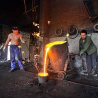 Chinese laborers pour molten iron at a foundry in Xiangfan, Hubei province, in this file photo. | REUTERS