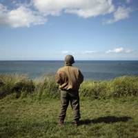 A man wearing a U.S. military uniform from World War II stares out over the beach of Arromanches-les-Bains, northwestern France, on Wednesday, two days before the 70th commemoration of D-Day. Memory collides with politics in Putin's 'Normandy landing'