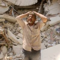 A man stands in front of the remains of a building bombed by Syrian regime forces in the northern city of Aleppo on Monday, a day ahead of the nation\'s presidential vote, which the opposition has labeled a sham. | AFP-JIJI