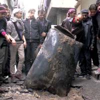 Syrians inspect an unexploded barrel bomb packed with explosives in January after a regime helicopter dropped it on a street in the city of Aleppo. | AP