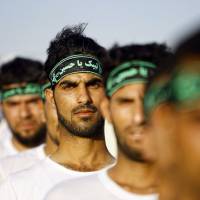 Shiite volunteers take part in a training session in the Iraqi shrine city of Najaf on Monday. They volunteered to protect holy sites in the event of an attack by Sunni militants from the Islamic State of Iraq and the Levant. | AFP-JIJI