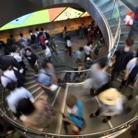 Customers descend a spiral staircase during the opening ceremony of Apple Inc.\'s Omotesando store in Tokyo on June 13. Consumer prices in May climbed at their fastest pace in 32 years, swelled by April\'s consumption tax increase, government data showed Friday.  | BLOOMBERG