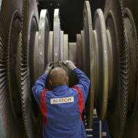 An Alstom employee measures a section of turbine at a facility for refurbishing power plant turbines located in Rugby, central England, in April. | BLOOMBERG