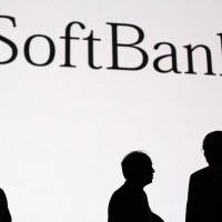 Masayoshi Son (center), chairman and chief executive officer of SoftBank Corp., and former U.S. Secretary of State Colin Powell (right), are seen in silhouette at SoftBank Academia, the company\'s training school, in Tokyo on Wednesday. | BLOOMBERG