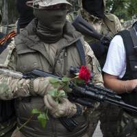 Pro-Russian fighters hold flowers after taking the oath of allegiance to the self-proclaimed \"Donetsk People\'s Republic\" in Donetsk, Ukraine, on Saturday. | AP
