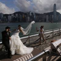 A couple takes wedding photos against the backdrop of Hong Kong\'s business district on Wednesday. The city will hold a controversial \"referendum\" on democracy on Friday, a prelude to an escalating campaign of dissent that could shut down the former British colony\'s financial district and further anger Communist Party leaders in mainland China. | REUTERS